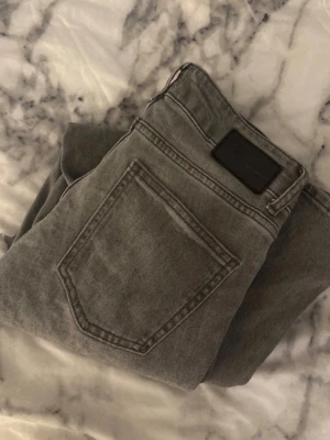 Grå bootcut jeans från 157 - Snygga grå jeans från 157 med bootcut passform och klassisk femficksdesign. Jeansen har en något tvättad look och är tillverkade i denim med en skön känsla. Perfekta för dig som gillar en avslappnad men trendig stil.