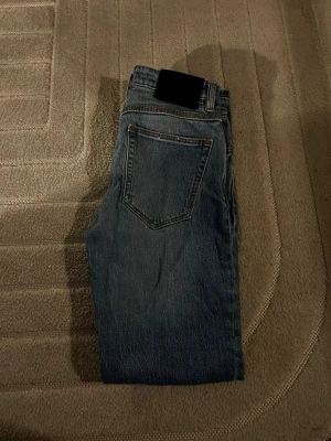 Neuw denim jeans - Säljer ett par klassiska blå jeans med raka ben och hög midja. Jeansen har två bakfickor och är sydda i ett slitstarkt denimtyg. Perfekta för en avslappnad och trendig look.