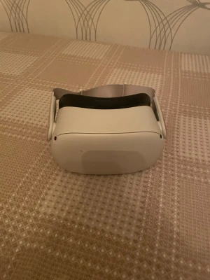 Oculus Quest 2 VR-headset med kontroller - Säljer ett Oculus Quest 2 VR-headset i vit plast med tillhörande handkontroller. Headsetet har en modern, rundad design och justerbart band för bekväm passform. Perfekt för gaming och VR-upplevelser hemma. Tillkommer med laddare.