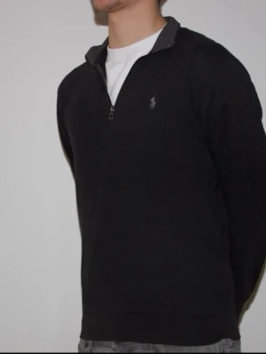 Svart halvzip från Ralph Lauren - Svart långärmad tröja från Ralph Lauren med halv dragkedja och klassisk broderad logga på bröstet.
