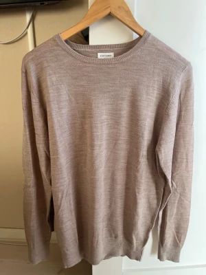 Beige tröja från A Day's March - Snygg och stilren beige tröja från A Day's March i storlek medium. Tröjan har rund halsringning, långa ärmar och är tillverkad i ett tunt, mjukt material som känns skönt mot huden. Perfekt för lager-på-lager och enkel att matcha med olika outfits.