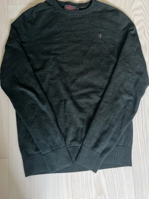  tröja från Morris - Klassisk grön tröja från Morris med rund halsringning och diskret logga broderad på bröstet. Tröjan har ribbade muddar vid ärmslut och nederkant, perfekt för en stilren look. Materialet känns mjukt och passar till många olika outfits.