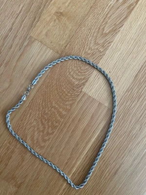 Snyggt tvinnat silverfärgat halsband - Ett stilrent halsband i silverfärg med tvinnad kedja. Halsbandet har en klassisk karbinhake och passar perfekt för att ge din outfit en extra touch.