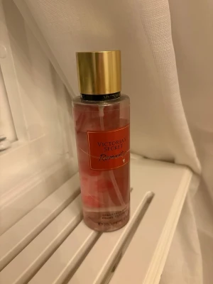 Victoria's Secret Romantic Body Mist - Fräsch body mist från Victoria's Secret i doften Romantic. Flaskan är genomskinlig med rosa toner och har ett elegant guldigt lock. Perfekt för dig som gillar blommiga och fruktiga dofter. Rymmer 250 ml och är enkel att ta med i väskan. Den är köpt för ett tag sedan och därför syns skador på plasten men inget är fel på burken🥰