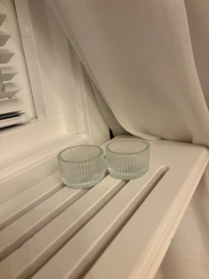 Två små räfflade glasbehållare - Säljer två små runda glasbehållare med räfflad yta. Perfekta som ljushållare, saltkar eller för småsaker. De är genomskinliga och har en stilren design som passar i de flesta hem.