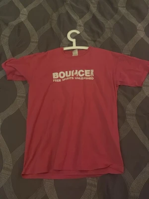 Röd BOUNCE INC t-shirt med tryck - Cool röd t-shirt från BOUNCE INC med vit text framtill och ett inspirerande citat på ryggen. Klassisk passform med korta ärmar och rund halsringning. Perfekt för dig som gillar streetwear och vill sticka ut med ett statement-plagg.