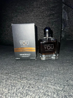 Emporio Armani Stronger With You Intensely  - Emporio Armani Stronger With You Intensely är en parfym med en elegant, fyrkantig glasflaska och silverfärgad rund kork. Doften kommer i en mörkgrå kartong med guldiga detaljer. Parfymen har en varm bärnstensfärgad vätska och rymmer 100 ml.
