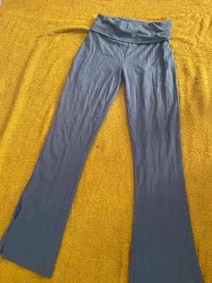 Mörkgrå utsvängda leggings - Snygga mörkgrå leggings med utsvängda ben och bred midjeresår. Perfekta för en avslappnad och trendig look. Mjukt och stretchigt material som sitter skönt hela dagen.