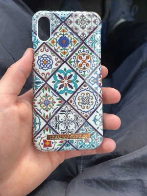 Mönstrat mobilskal från iDeal of Sweden - Snyggt mobilskal med färgglatt kakelinspirerat mönster i blått, grönt, orange och vitt. Skalets design har flera geometriska former och detaljerade ornament. Passar till iPhone-modeller med kameraöppning i hörnet. Tillverkat i hårdplast.