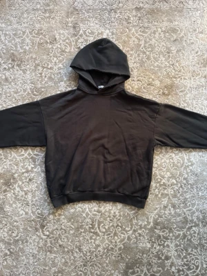 Svart hoodie Acne studios - En stilren svart hoodie med huva och ribbade muddar vid ärmslut och nederkant. Hoodien har en avslappnad passform och är tillverkad i mjukt material, perfekt för en casual look. Inga tryck eller loggor syns på framsidan.
