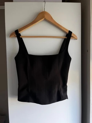 Svart korsett-topp med breda axelband - Snygg svart korsett-topp med breda axelband och markerade sömmar framtill. Så fin att styla till ett par snygga jeans eller kostymbyxor! Från Zara