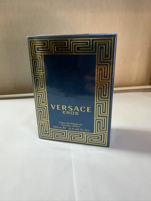 Versace Eros Eau de Parfum 100ml - Versace Eros Eau de Parfum i en lyxig blå och guldig förpackning med klassiskt grekiskt mönster. Flaskan rymmer 100 ml och är perfekt för dig som gillar exklusiva och intensiva dofter. Märket är känt för sin eleganta och moderna stil.