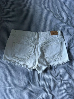 Vita jeansshorts med fransig sopkant - vita jeansshorts från gina med fransig kant och klassisk femficksmodell.❤️