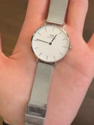 Daniel Wellington silver meshklocka - Stilren klocka från Daniel Wellington med vitt ur och silverfärgat mesharmband i rostfritt stål. Minimalistisk design med tunna svarta index och DW-logga på urtavlan. Perfekt accessoar för en clean look. Batteriet fungerar INTE längre!🥹🧸🩷