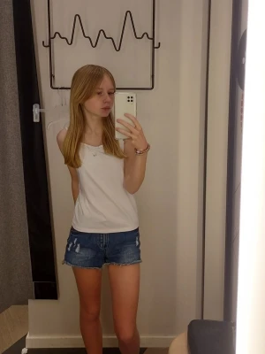 Blå denimshorts med slitningar - Snygga blå denimshorts med slitna detaljer framtill. Klassisk femficksmodell och råa benslut ger en avslappnad look. Perfekta för varma dagar och enkel att matcha med olika toppar.