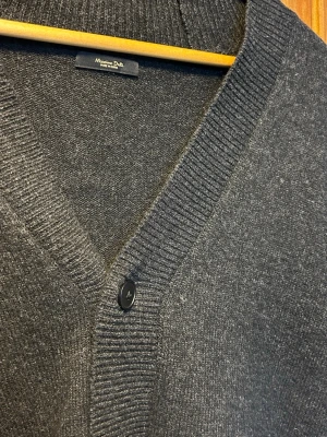 Stickad Kofta || Massimo Dutti - Tjenare! Säljer denna sköna koftan från Massimo Dutti! Det är en mörkgrå stickad kofta med v-ringning och 5 knappar framtill. Koftan har bred ribbad kant vid halsen och ärmarna. Perfekt för lager på lager och enkel att matcha med olika outfits. Hör av er vid fler frågor och liknande!