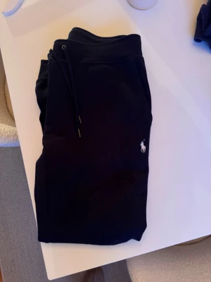 Svarta mjukisbyxor från Ralph Lauren - Säljer ett par svarta mjukisbyxor från Ralph Lauren med klassisk vit logga på benet. Perfekta för chill dagar och riktigt sköna att ha på sig. 
