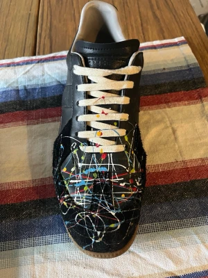 Maison Margiela GAT Paint Splatter - Tja! Säljer ett par riktigt feta gats. Dom är använda i 7 månader. Har tecken på användning som syns på snören samt tecken vid färgen. Dessa skor är i ett skick där jag rekkomenderar för vardaglig använding. Jag har använt en annan innersula för att garantera hygien.  Dessa skor är replicas, hör av dig vid meddelande vid minsta lilla fråga, Jag svarar på allt. OBS Innan jag skickar skorna ger jag mitt bästa försök på att rengöra dom. Medföljande är bara skorna i paketet. Öppen för erbjudande 