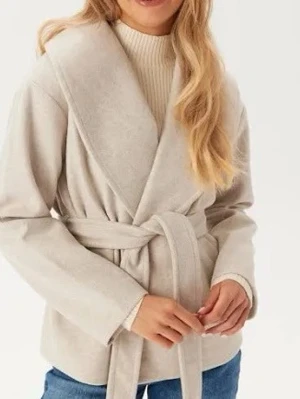 Beige omlottkappa från ONLY - Säljer en beige kappa från ONLY med snygg omlottmodell och bälte i midjan. Jackan har långa ärmar, bred krage och är i ett mjukt material som känns lyxigt. Perfekt för dig som gillar stilrena och enkla plagg.