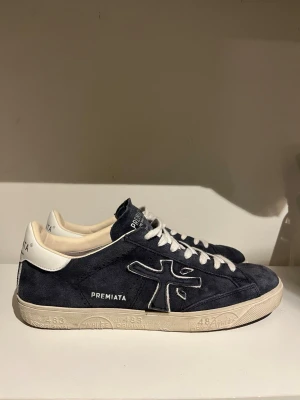 Premiata - Snygga mörkblå sneakers från Premiata i mjuk mocka med vita detaljer och vita skosnören. Skorna har en låg silhuett och en beige sula med mönster. Klassisk logga på sidan och bekväm innersula.
