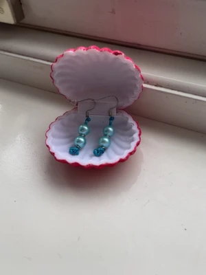 Turkosa pärlörhängen med silver detaljer handgjorda  - Säljer ett par handgjorda örhängen med turkosa pärlor och silver detaljer 