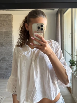 Vit blus med spetsdetaljer - Säljer en luftig vit blus med v-ringning och volangkant. Blusen har långa ärmar med  spets och lätt rynkade detaljer. Är i största storleken från barn avdelningen men sitter som en xs💕