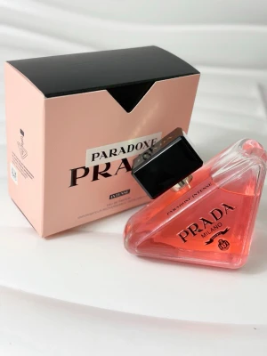 Prada Paradoxe Intense 90ml - Prada Paradoxe Intense är en pipelineformad parfymflaska i glas med rosa-orange doftvätska och svart lock. Flaskan har en modern, unik design och kommer i en stilren ljusrosa kartong med svart lock. sopar in dofttrender och är perfekt för dig som gillar exklusiva parfymer.