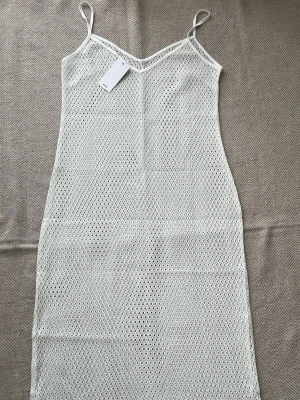 Vit strandklänning från Mango mng - Snygg vit strandklänning från Mango i genombruten virkad stil. Klänningen har sopiga axelband och V-ringning sopm ger en avslappnad beachlook. Perfekt att dra över bikinin på stranden. Materialet är lätt och luft tied för sopmrig känsla. Passar S M L Xl nypris 1100kr