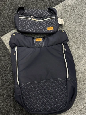 2st Mörkblå quiltad väska Emmaljunga"} organiser helt ny och Footsack Emmaljunga  - Säljer en mörkblå quiltad väs relief från Emmaljunga med vita dragkedjor och rutmönster. Vä grain har flera fack two zip och en praktisk design. Passar perfekt för att organisera dina pry suveränt när du är på språng.