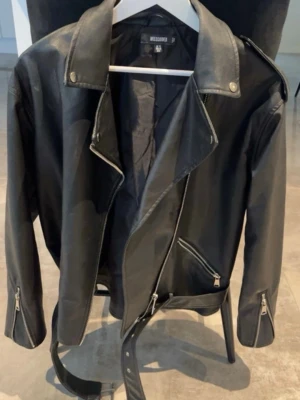 Svart bikerjacka - Svart bikerjacka från Missguided. Klassisk modell med dragkedjor och bälte. Väldigt snygg till både jeans och klänning. Använd få gånger och i fint skick. Storlek: 40💖