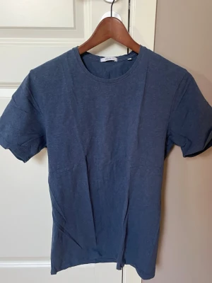 Mörkblå t-shirt från Bläck - En stilren mörkblå t-shirt från Bläck med klassisk rund hals och korta ärmar. Tillverkad i mjuk bomull som känns skön mot huden. Perfekt basplagg att matcha med jeans eller shorts.