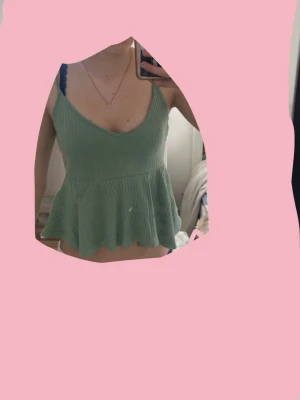 Grön ribbad linnetopp med volang - Söt ljusgrön linnetopp med breda axelband och v-ringning. Toppen är ribbad och har en volang nedtill som ger en flowy känsla. Perfekt för varma dagar och enkel att styla med jeans eller kjol.