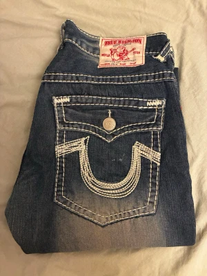 True Religion jeans - Säljer sköna true religion jeans. Storlek 38 mycket fint skick endast minimalt med heeldrag. Mått: midja tvärs över 50cm, längd från midja till ben öppning 112cm och bredd ben öppning 26cm. 