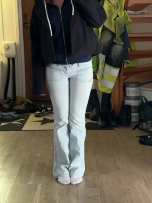 Ljusblå bootcut jeans från Diesel - Säljer ett par ljusblå jeans från Diesel med bootcut passform och dubbla knappar i midjan.  Jeansen har stora framfickor med blå/svarta detalier och en liten Diesel-logga på ena fickan. Tillverkade i mjukt denimtyg, perfekta för en avslappnad stil.