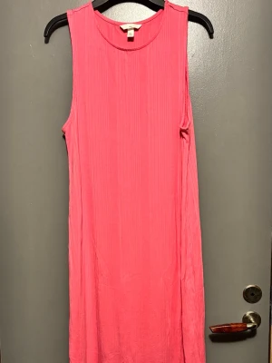 Rosa ribbad ärmlös klänning H&M - Snygg rosa ärmlös klänning med ribbad struktur och slits på sidan. Perfekt för varma dagar och enkel att styla med accessoarer. Mjuk och bekväm, passar dig som gillar en avslappnad men trendig look.