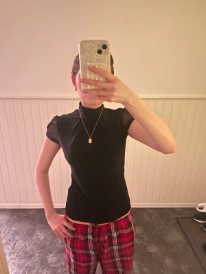 Svart polotopp med puffärm - Snygg svart polotopp med korta puffärmar och figurnära passform. Toppen har en hög krage och är tillverkad i ett stretchigt material som sitter bekvämt. Perfekt att styla med både jeans och kjol för en trendig look. Storlek 42 men jag har 34,36 och de passar perfekt