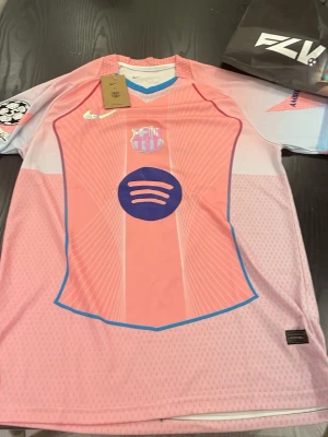FC Barcelona Raphinha #11 fotbollströja - Säljer en riktigt snygg FC Barcelona tröja special edition med Raphinha #11 på ryggen. Tröjan har en unik rosa design med blå detaljer och Spotify-sponsor, vilket gör att den sticker ut och ser väldigt clean ut.  Den har fortfarande taggen och har inte använts. Kommer med full presentation                  •	Storlek: M (herr) 	•	Passar ungefär: ca 170–180 cm (beroende på hur man vill att den ska sitta) 	•	Spelare: Raphinha 	•	Nummer: 11 	•	Klubb: FC Barcelona 	•	Skick: Ny med tags