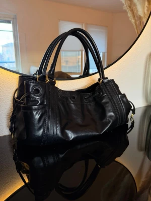 Handväska - Zara - Svart handväska med guldiga detaljer från Zara. Två innerfack med dragkedja. Använd men i fint skick! 