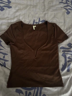 Brun v-ringad topp Nelly - Snygg brun topp från Nelly med djup v-ringning och korta ärmar.