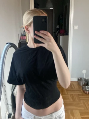 Svart croppad t-shirt - En enkel svart croppad t-shirt med rund hals och korta ärmar. Perfekt för dig som gillar en clean och stilren look. T-shirten har en loose passform och är gjord i mjukt bomullsmaterial.