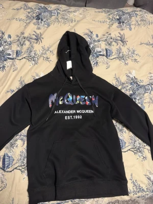 Svart hoodie Alexander McQueen - Snygg svart hoodie från Alexander McQueen med färgglad logga på bröstet. Passar S/M
