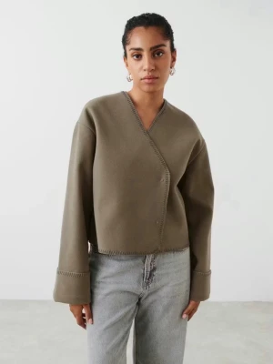Beige kofta från Gina Tricot  - Säljer en beige kofta från Gina Tricot med v-ringning och dekorativa sömmar. Tröjan har långa, vida ärmar och är tillverkad i ett mjukt material som ger en avslappnad look. 