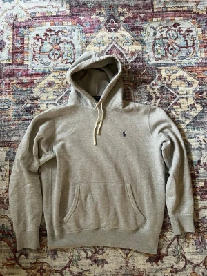 Grå hoodie från Polo Ralph Lauren - Snygg grå hoodie från Polo Ralph Lauren i storlek M med klassisk broderad logga på bröstet. Hoodien är i mycket gott skick och såklart ÄKTA. Kontakta vid minsta fråga🤗