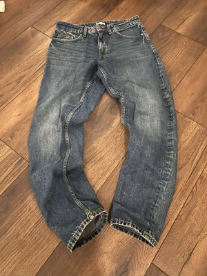 Blå jeans från Cubus - Säljer ett par klassiska blå jeans i straight fit med normal passform. Jeansen har fem fickor, dragkedja och knapp framtill samt snygga slitningar och tvättade detaljer. Perfekta till en chill vardagslook.