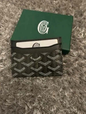 Svart kortfodral från G@yard - Snyggt svart kortfodral från G@yard med det klassiska vita och gråa mönstret. Tillverkat i tåligt canvasmaterial med plats för flera kort. Perfekt för dig som vill ha en stilren och exklusiv accessoar i fickan. Pris kan diskuteras