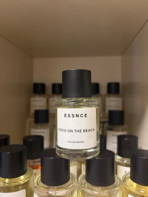 ESSNCE Coco On The Beach parfym - Fräsch Eau de Parfum från ESSNCE med namnet Coco On The Beach. Flaskan är genomskinlig med rund form och har en svart matt kork. Etiketten är vit med minimalistisk text. Perfekt för dig som gillar tropiska och somriga dofter.