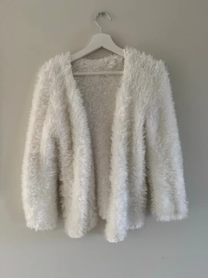 Vit fluffig kofta  - Supermjuk och fluffig vit kofta. Vet inte vart den är ifrån och kan därför inte veta vad storleken är. Men skulle säga att den passar xs-l och är i bra skick.