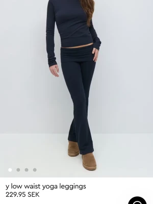 Blå och vinröda low waist yoga leggings - Säljer ett par svarta low waist yoga leggings med utsvängda ben. De har en bred linning och sitter snyggt på höften. Perfekta för en avslappnad och trendig look. Storlek 152