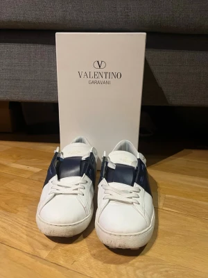 Valentino Garavani vita sneakers - Snygga vita sneakers från Valentino Garavani med marinblå detaljer. Mycket fint skick 9,5/10 endast använda ungefär 5-6 gånger. Hör gärna av er vid frågor/intresse. Löser frakt samma dag :)