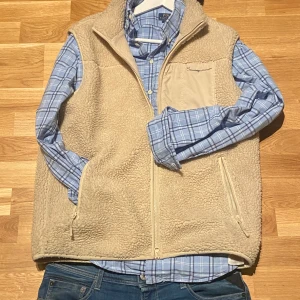 Beige fleeceväst från Knowledge Cotton Apparel - Säljer en mysig beige fleeceväst från Knowledge Cotton Apparel. Västen har dragkedja framtill och två praktiska fickor med dragkedjor. Perfekt för lager-på-lager under kyliga dagar. Båda fickor trasig inuti.